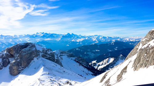 Scenic view of snowcapped mountains against blue sky