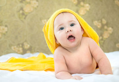 Portrait of baby girl lying with towel on head at home