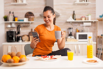 Young woman using phone while sitting at home