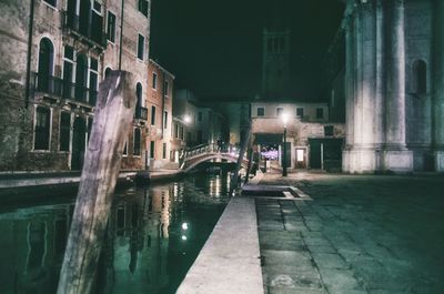 Buildings by canal in city at night