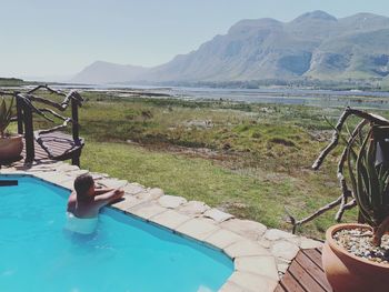 Swimming pool by mountains against sky