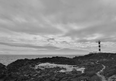 Lighthouse by sea against sky