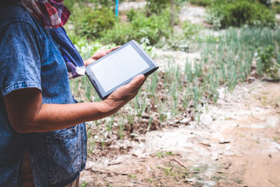 Midsection of man using digital tablet while standing on field