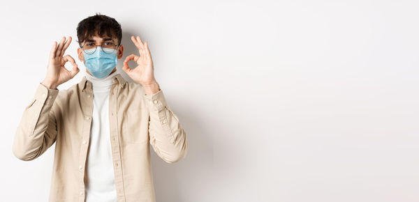 Portrait of young woman wearing mask against white background