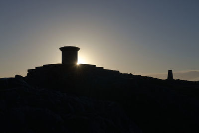 Low angle view of silhouette rock formation against clear sky