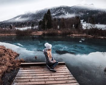 Man standing on lake by trees during winter