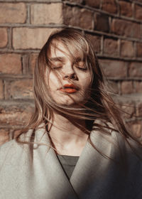 Portrait of young woman against wall. hair and wind