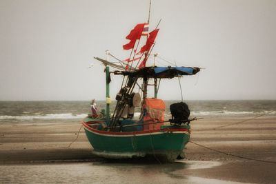 Fishing boat on beach against clear sky