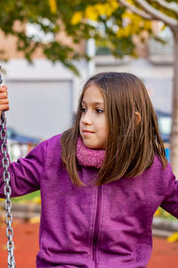 Thoughtful girl sitting on swing at playground