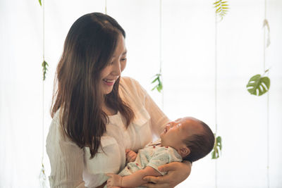 Happy mother with baby standing at home