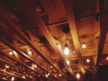 Low angle view of illuminated pendant lights hanging from ceiling