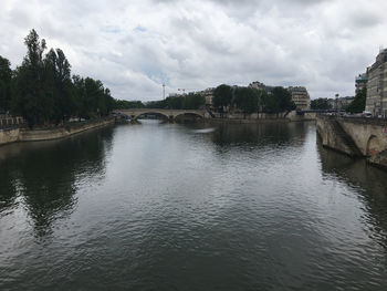 Bridge over river in city against sky