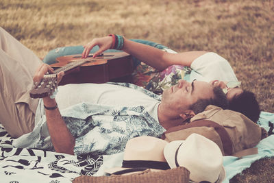 Couple with guitar lying on blanket