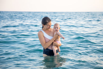 Mother and daughter in sea against sky