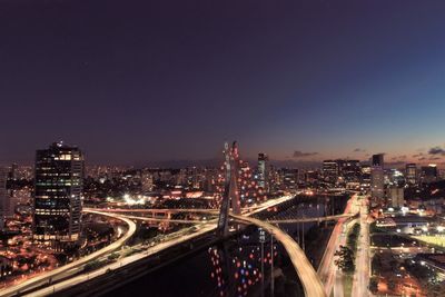 Illuminated bridge and buildings against sky at night