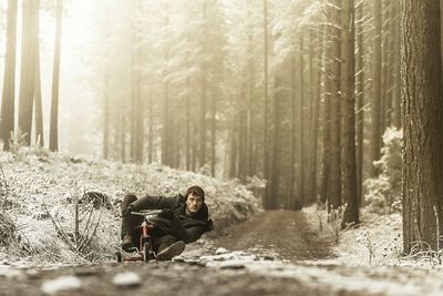 Woman standing on tree trunk in forest
