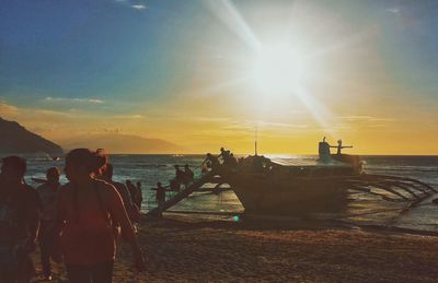 Silhouette people standing on beach against sky during sunset