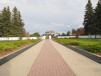 Footpath leading to built structure against sky