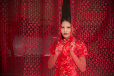 Portrait of smiling woman standing against red wall