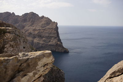 Scenic view of cliff by sea against sky