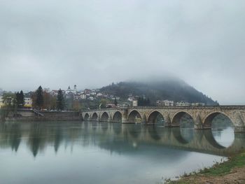 Arch bridge over river against sky