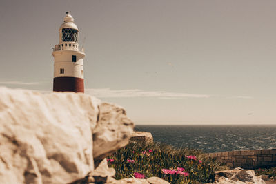 Lighthouse by sea against sky