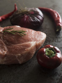 High angle view of pork with rosemary and chili peppers on table