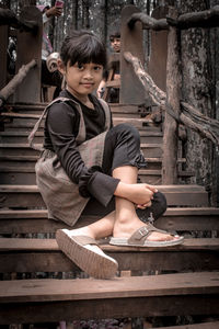 Portrait of boy looking away while sitting on wood