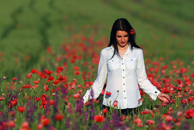 Young woman standing by poppy field