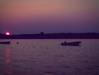 Boats in sea at sunset