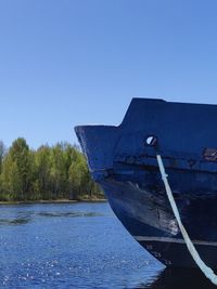 Boat moored in lake against clear blue sky