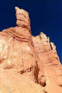 Low angle view of rock formations against clear blue sky