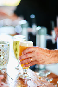 Cropped hand of person holding beer on table