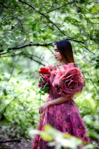 Woman standing by tree against plants