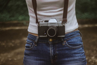 Close-up midsection of woman with camera standing outdoors