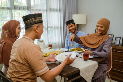 Smiling woman serving food to guests at home