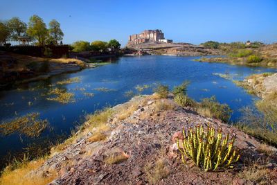 Scenic view of lake by mehrangarh fort against clear blue sky