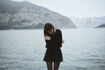 Woman standing by lake against mountains