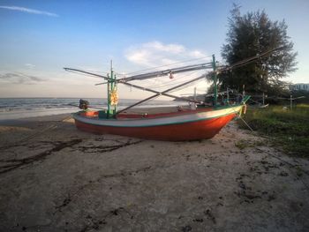 Boat moored on beach against sky