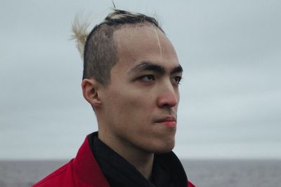 Portrait of young man looking away against sky