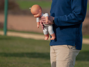 Midsection of man holding doll while standing field