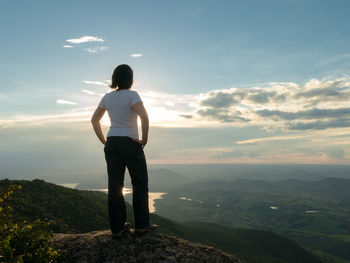 Rear view of man standing on mountain against sky