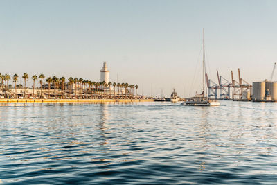 Sailboats in sea against buildings in city