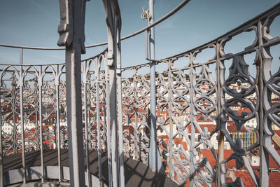 Low angle view of railing by building against sky