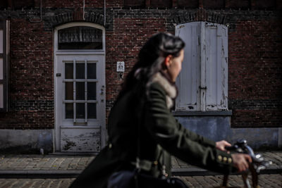 Side view of woman riding bicycle against old building in city