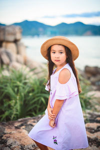 Portrait of girl wearing hat while standing at lakeshore