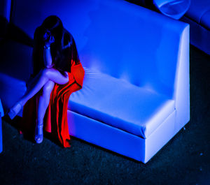 Woman sitting against blue wall