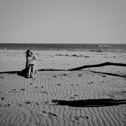 Rear view of woman on beach against clear sky