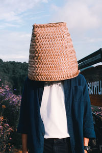 Man covering head with basket standing in backyard