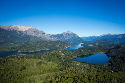 Scenic view of lake and mountains against clear blue sky